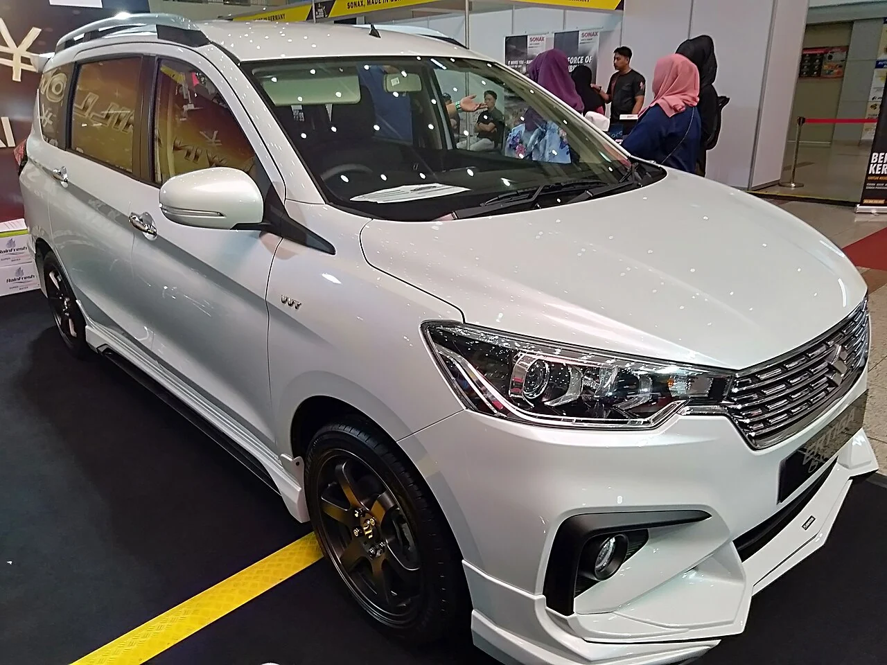 Representative photo of a white Maruti Suzuki Ertiga displayed at a motor show; actual availability is confirmed directly
