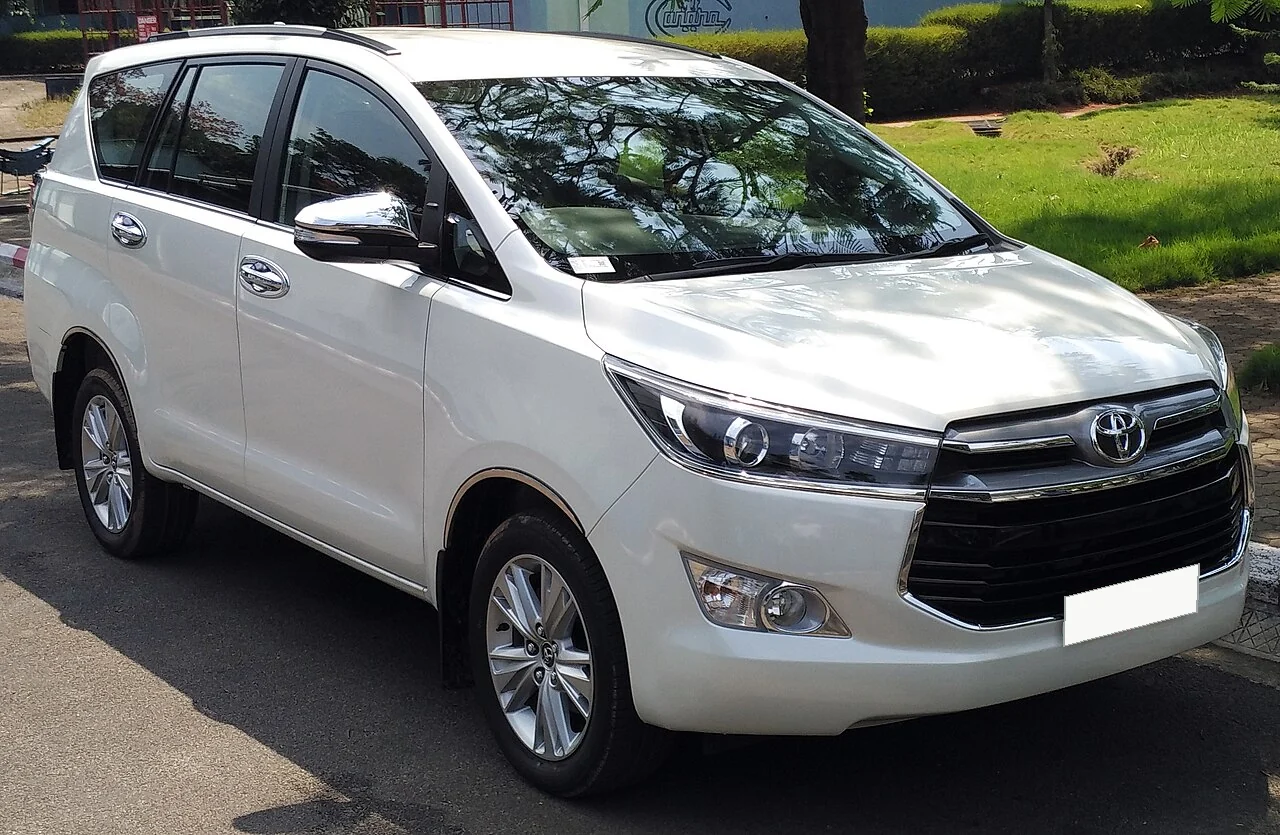 Representative photograph of a white Toyota Innova Crysta; actual model and date-specific availability require confirmation.